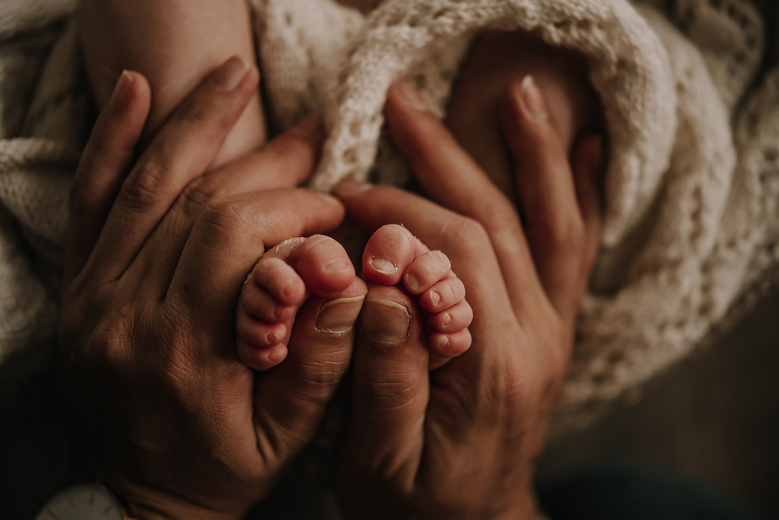 Piececitos de bebé sostenidos por manos adultas